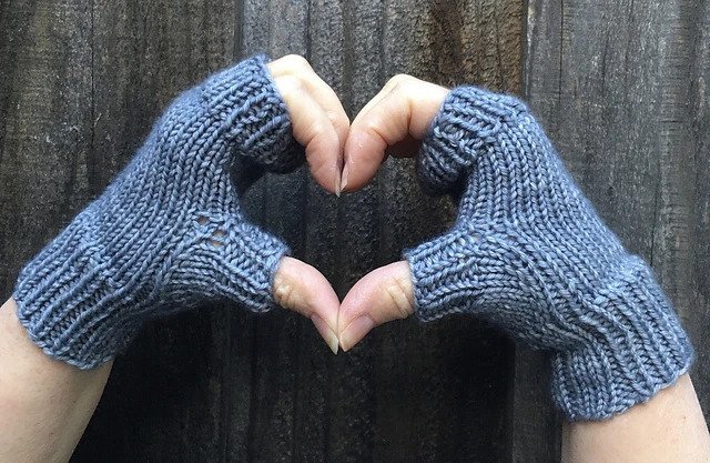 A pair of hands forming a heart shape wearing Christine's Boardwalk fingerless mitts 