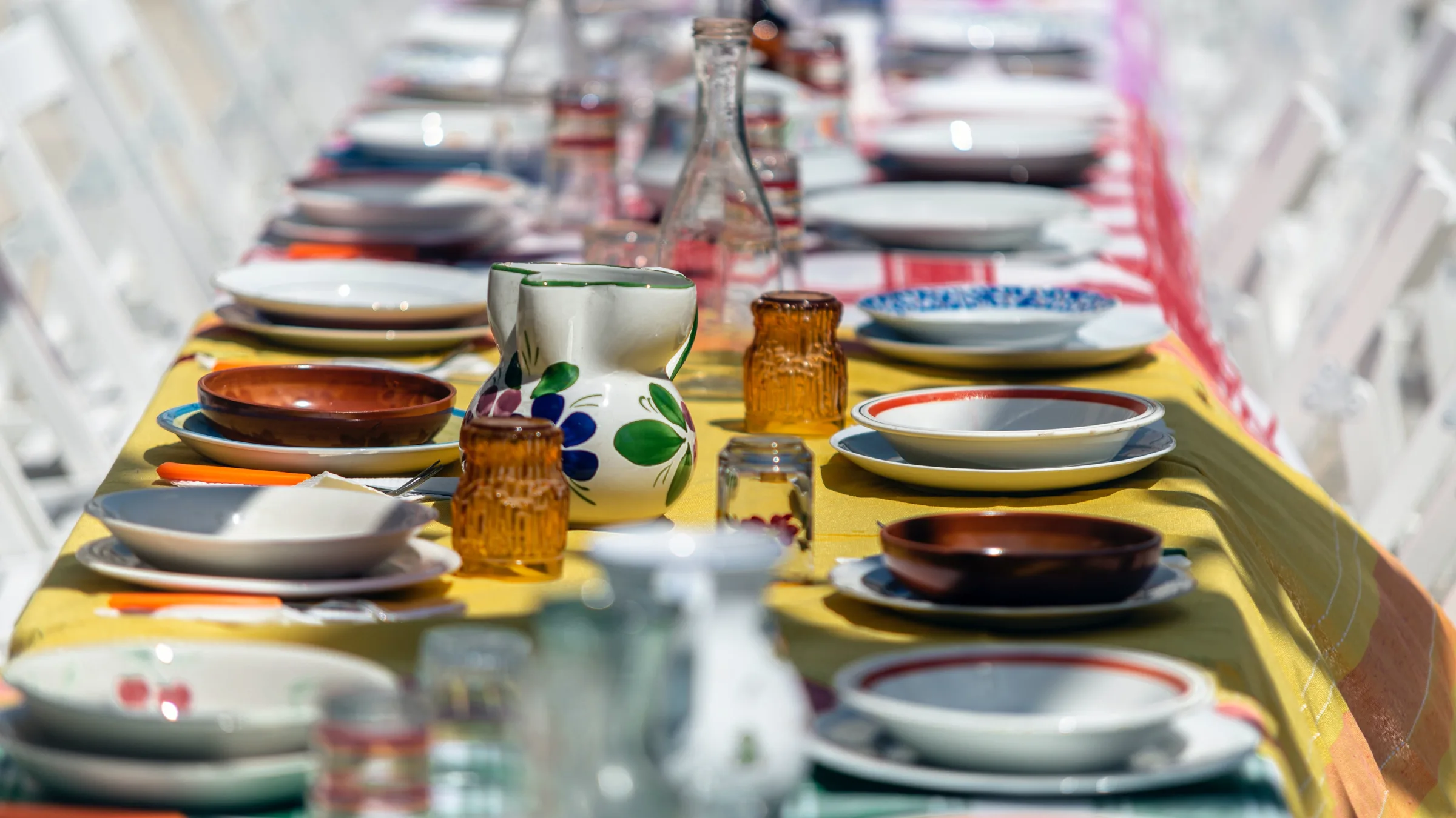 Row of mismatched table settings across a dining table.